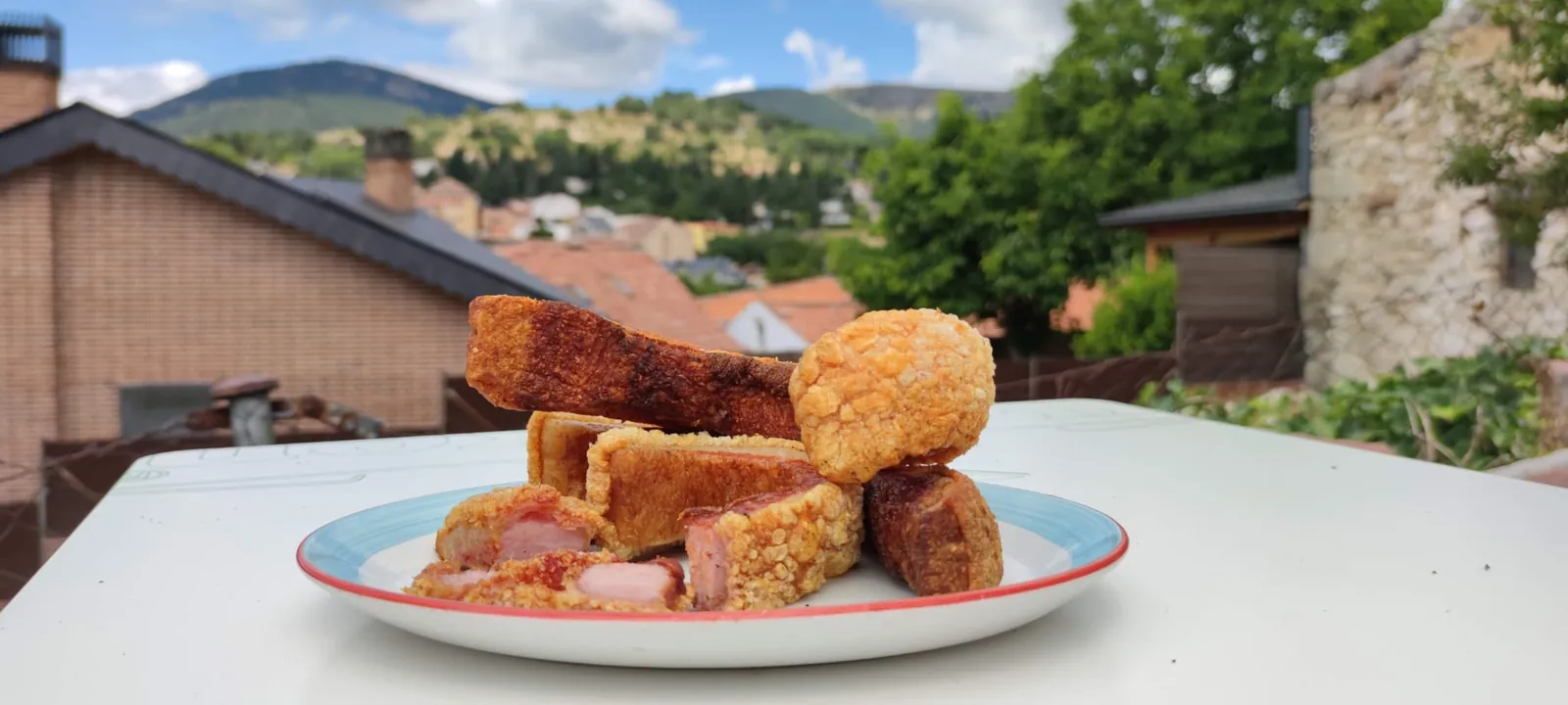 Ración de torreznos en la terraza de El Rancho de Javi con Cercedilla y la sierra al fondo